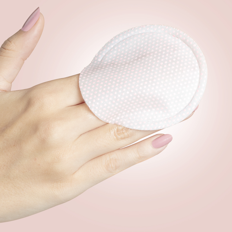 Hand hält eine runde, gepunktete Gesichtsmaske von STARSKIN vor einem rosa Hintergrund.