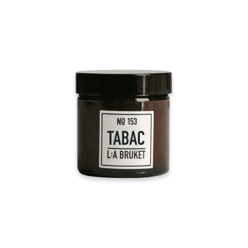 Ein Glas mit schwarzem Deckel und Etikett 'No 153 Tabac L:A Bruket' auf grünem Hintergrund.