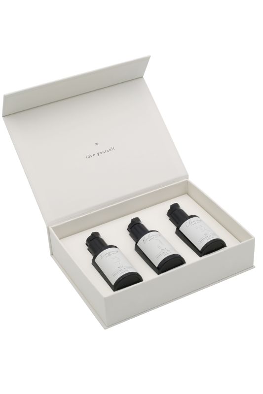 Offene weiße Box mit drei schwarzen Flaschen, beschriftet mit 'love yourself'.